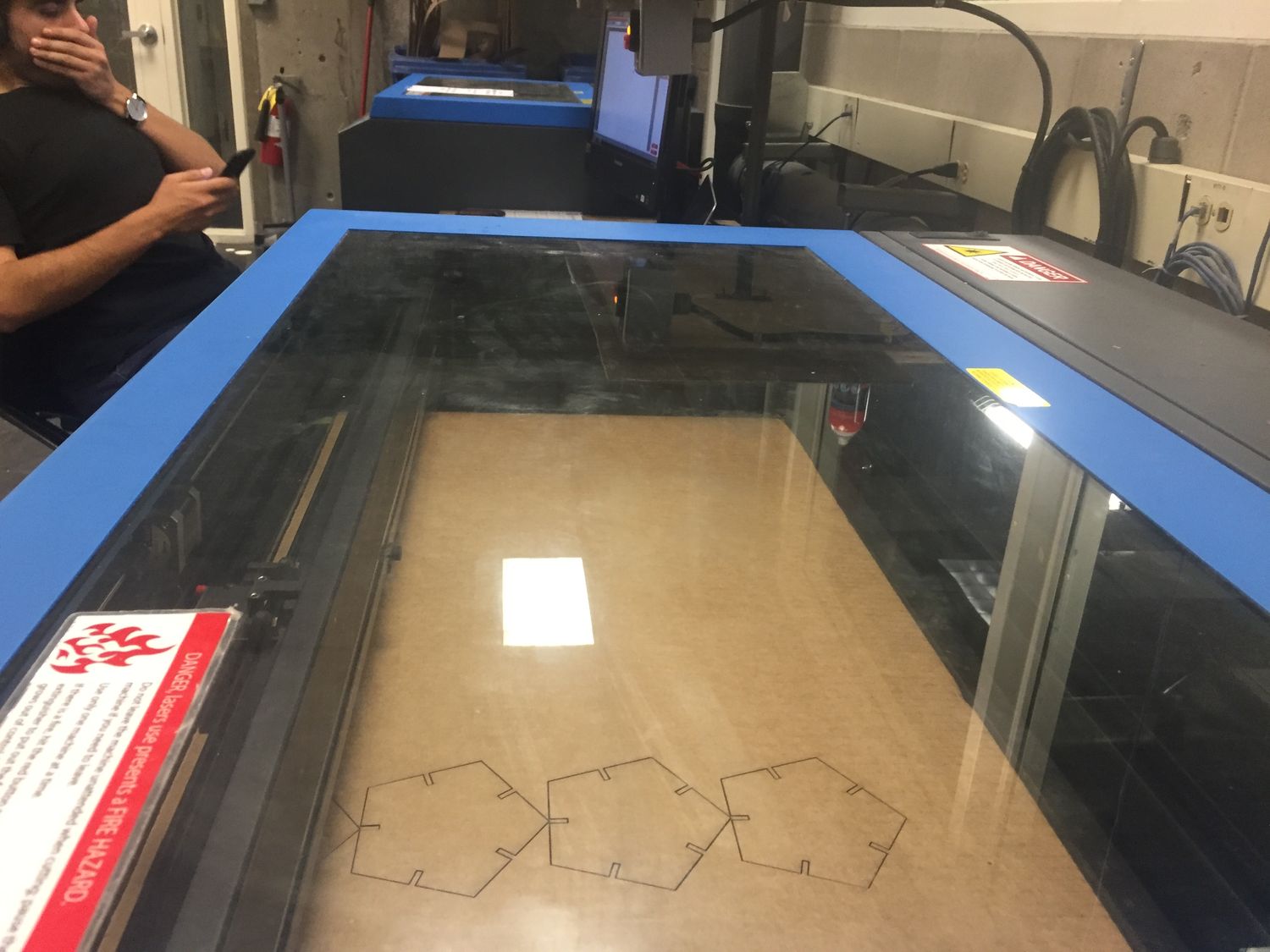 Blue laser cutting machine with a person yawning in the background