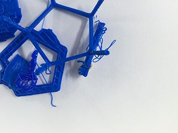 An unsuccessful 3D print showing blue plastic objects strewn around against a white background