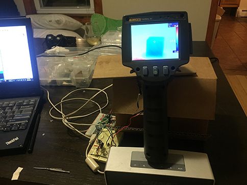 Heat gun camera positioned atop of a cardboard box on a messy table