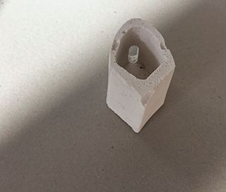 Small white plaster object on a grey background