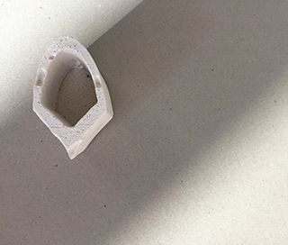 Small white plaster object in on a grey background viewed from the top