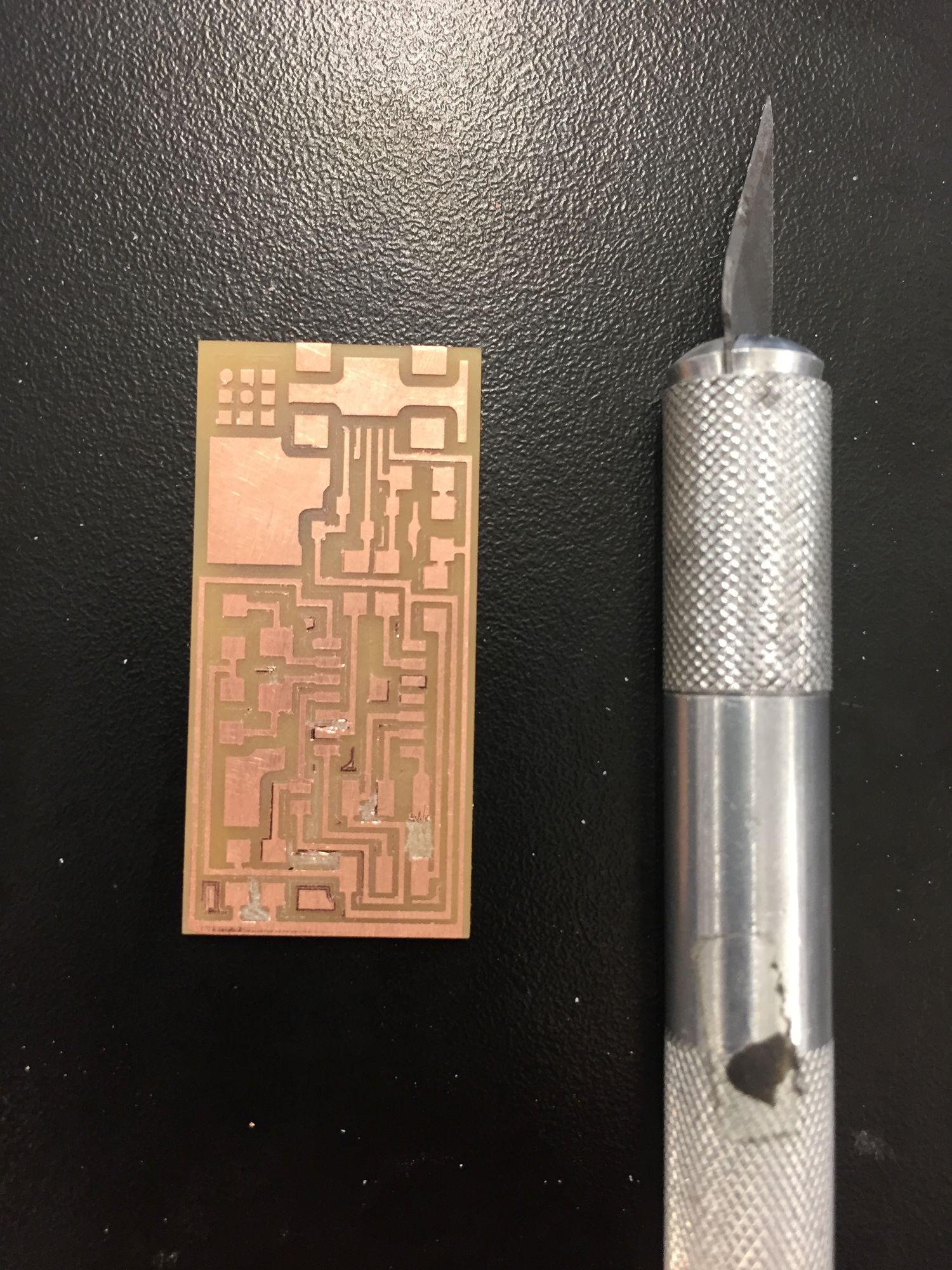 Copper circuit board and an X-Acto knife against a dark background
