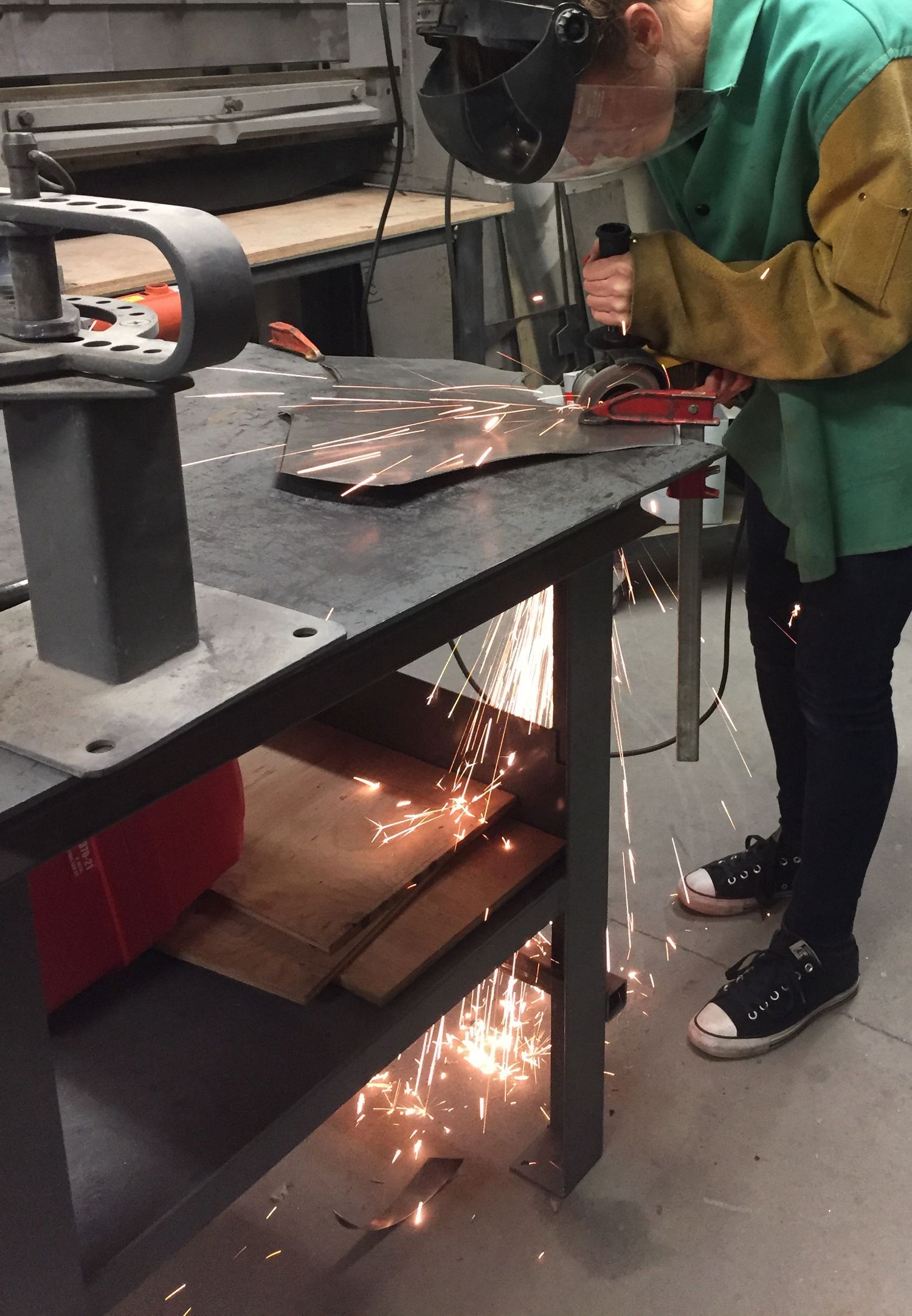 Female bent over a table with a tool that is generating sparks