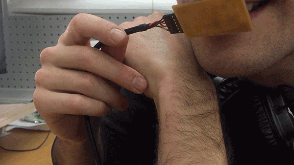 Close up of a male holding a circuit board to his mouth that continuously lights up and dims