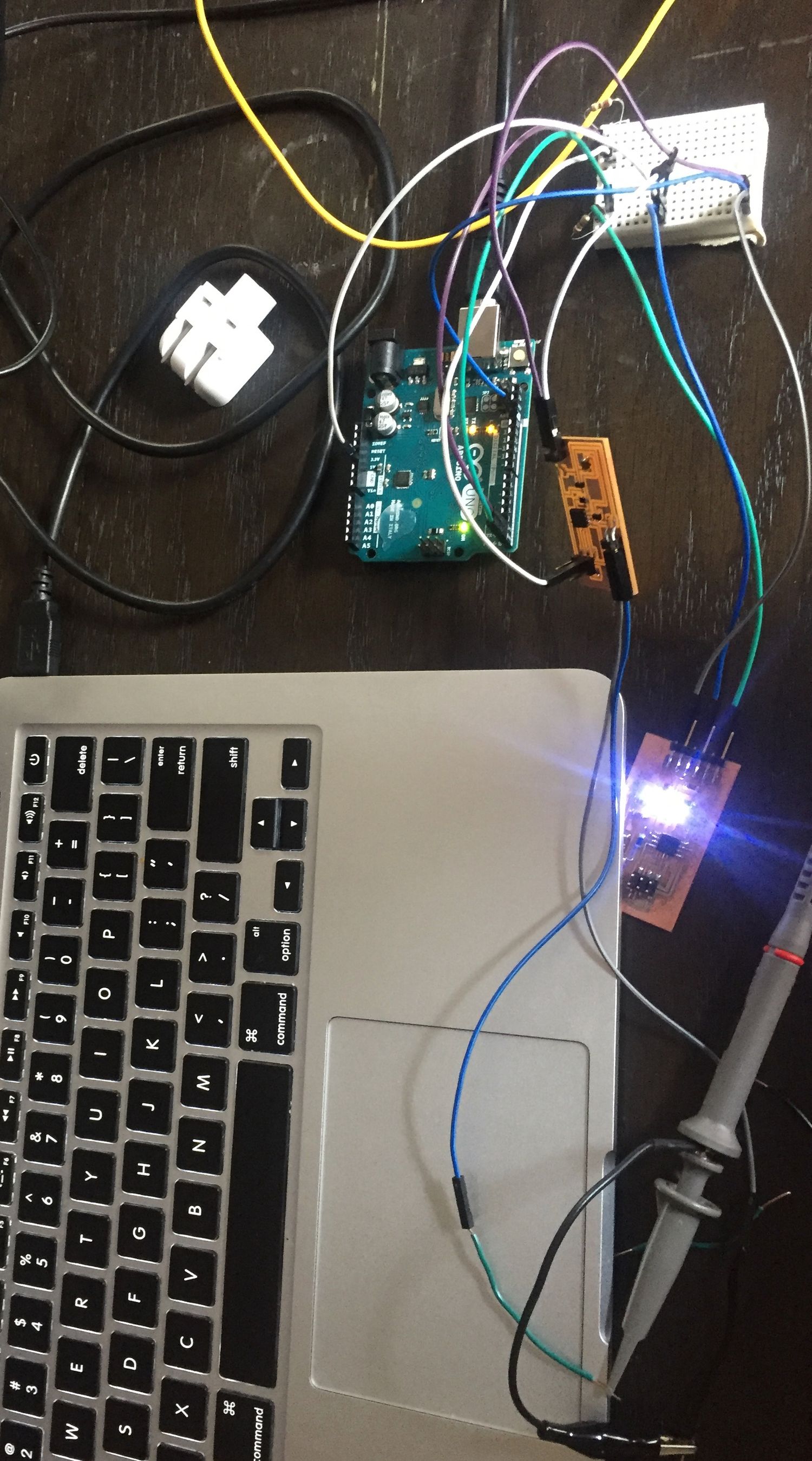 Lots of wires, a breadboard, laptop, and an Arduino on a dark table