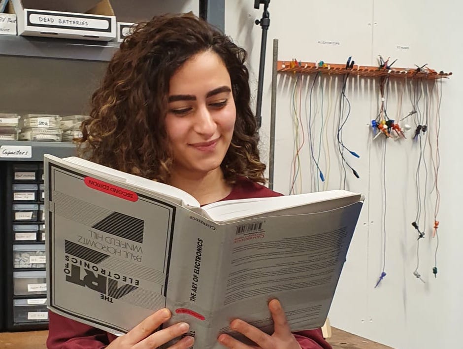 Rehana reading the OG of books: the Art of Electronics, upside down