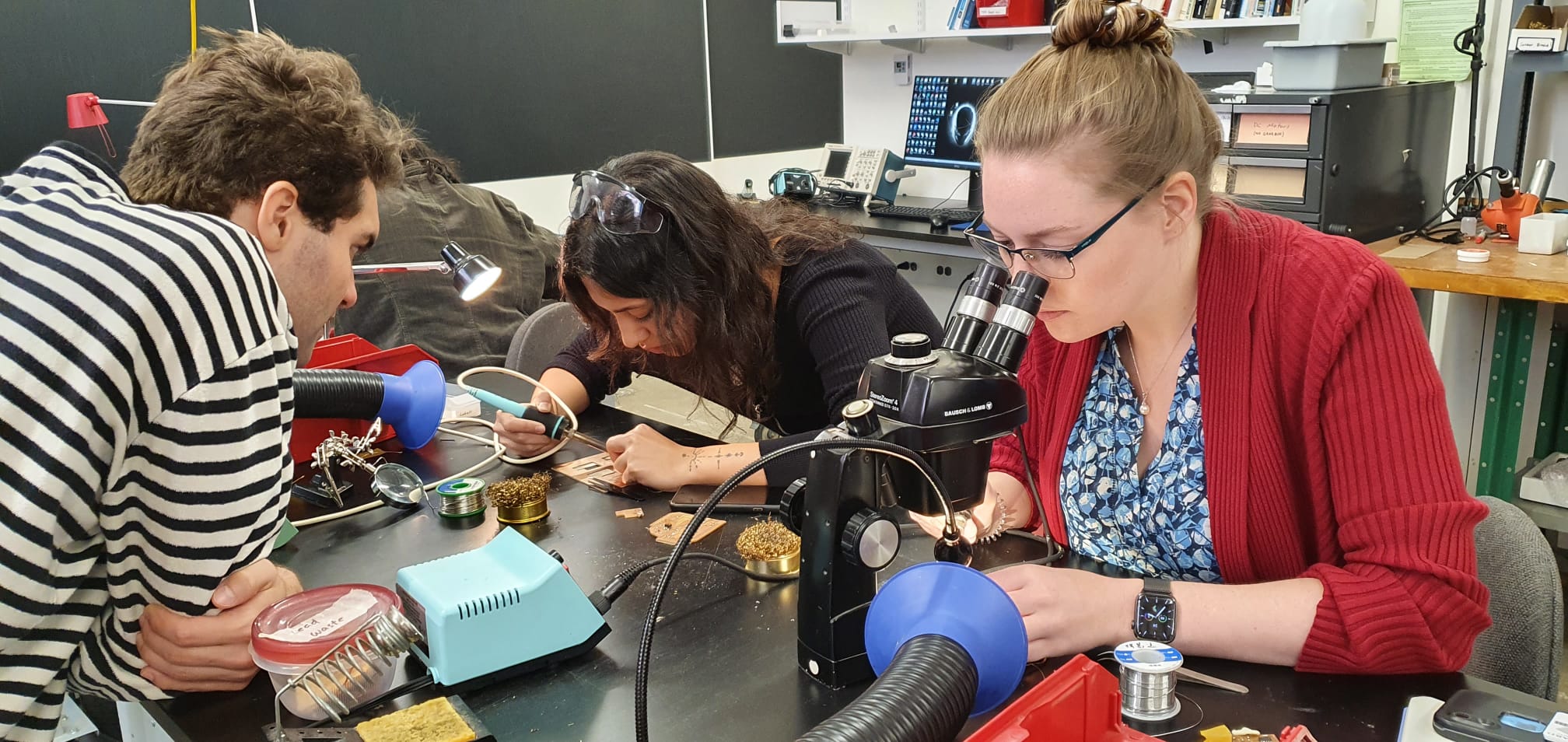 Image of a group of people soldering on a table