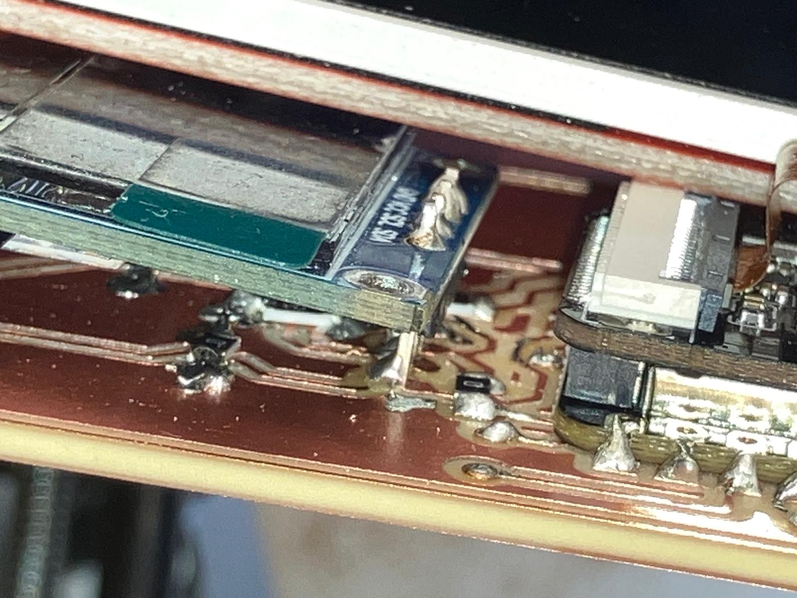 Close-up of further ripped copper traces near the acrylic edge