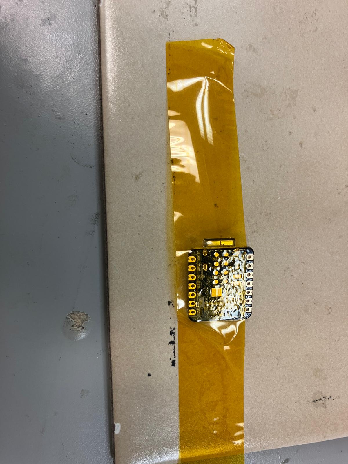 Board with microcontroller footprint masked using Kapton tape